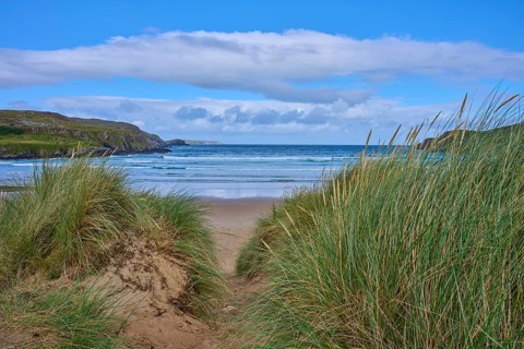 A passageway through the dunes leads to a sandy beach with views of the sea and sky, Farr Bay,