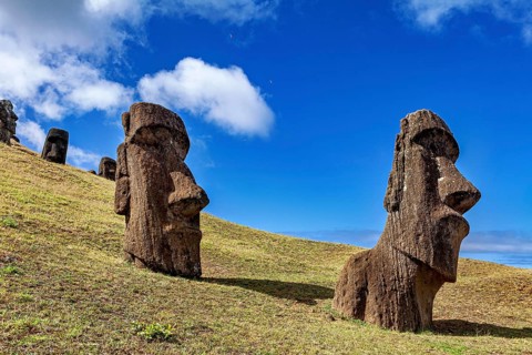 Two Moai statues stand side by side on a grassy hill under a blue sky, The Moai Statues on Easter