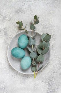 Easter colored eggs, in turquoise tones, on a gray plate, with a branch of eucalyptus, Easter card,