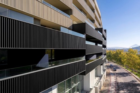 This image showcases a contemporary apartment building with vibrant balconies and sustainable