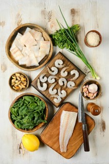 The kitchen countertop displays an assortment of fresh seafood and vibrant vegetables, including