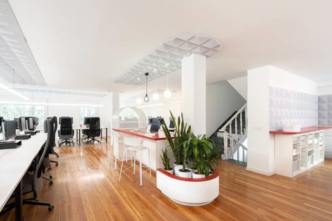 A modern open space office features sleek, ergonomic chairs and desks with monitors, complemented