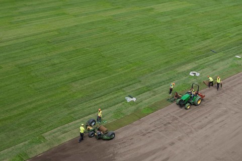 Workers laying grass in a roll on a football field at the stadium in Lubin, Poland