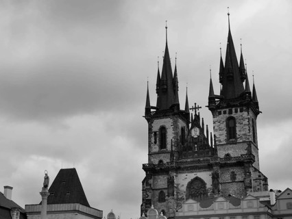 Tyn Church, Gothic church with distinctive towers and dramatic clouds in black and white, Prague