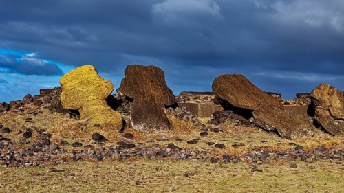 Fallen moai lie on a rocky surface against a cloudy sky, the moai statues on Easter Island in the