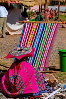 Woman wearing traditional clothes at a loom in a rural setting, elderly traditionally dressed lady