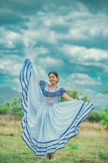 Smiling yung woman wearing traditional Nicaraguan folk costume in a field. Happy girl in national