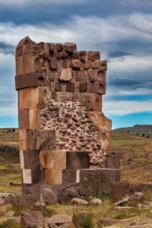 Textured stone ruin with remnants of walls against a cloudy sky, The Chullpas of Sillustani near