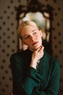 A serene portrait of a teenager in a green shirt, thoughtfully posing indoors against a stylish