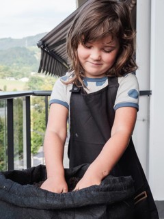 A young girl, with a gentle smile, is caught fully immersed in planting sunflower seeds in a fabric