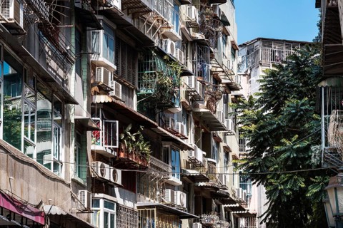 A detailed view of older buildings in Macau featuring barred balconies, designed for security,