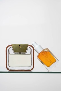 Elegant pipette bottle of vitamin C serum next to a sleek perfume bottle with a golden cap Both