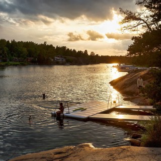 Picturesque swimming area, visitors at the jetty, idyllic Scandinavian landscape, Sound, sunset,
