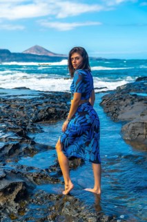 Young woman walking barefoot on volcanic rocks in the beautiful coastal town of arucas, gran