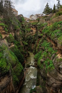 El Tajo gorge showing the Guadalevin river and a wooden walkway along the steep mossy cliffs in