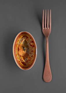 Top view of a ceramic dish featuring a single mussel in flavorful, saucy broth, accompanied by a