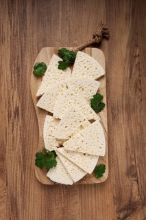 Sliced Georgian cheese, factory grade, on a wooden board, top view