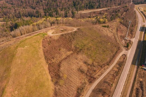 Aerial view of a hill surrounded by roads in the forest with bare and vegetated areas, old deposit