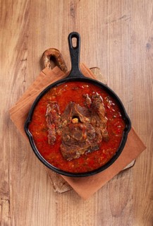 Fried steak, veal neck on the bone, stewed with vegetables, in tomato sauce, cooking meat, in a