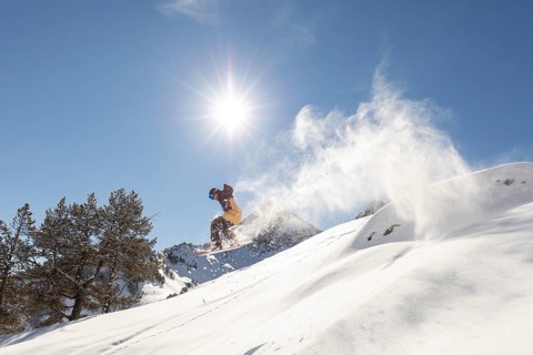 A dynamic image captures a snowboarder effortlessly gliding through untouched powder in a