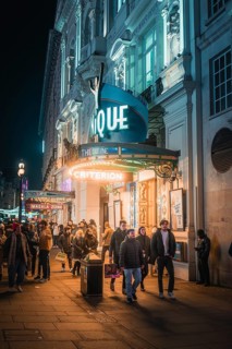 Busy street at night in front of an illuminated theatre with passers-by and urban flair, New Year's