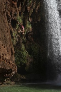 OUZOUD, MOROCCO - OCTOBER 5, 2024: A Moroccan young man jumps from the high rock into the water