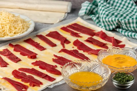 Puff pastry topped with ham and surrounded by other ingredients such as egg and cheese