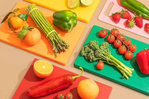A vibrant arrangement of fresh fruits and vegetables on colorful cutting boards. Includes tomatoes,