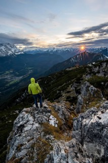 View Mountain panorama at sunset with sun star, mountaineer at the summit of the Kramerspitz, in