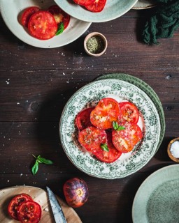 A beautifully arranged display of juicy tomato slices sprinkled with herbs and salt, set on vintage