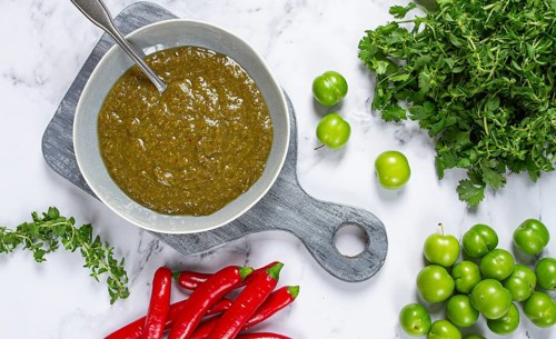 Tkemali sauce, made from green cherry plum, with ingredients on the table, top view, Georgian