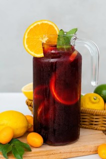A chilled pitcher of sangria garnished with fresh orange slices and mint sprigs, resting on a