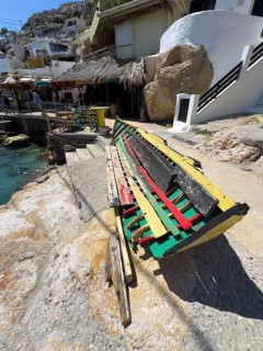Old painted fishing boat halved and converted into a bench, painted with hippie Rastafarian