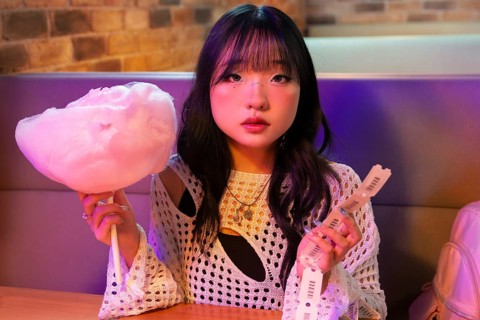 Asian Gen Z girl enjoys a fun day, holding cotton candy and tickets The vibrant setting reflects
