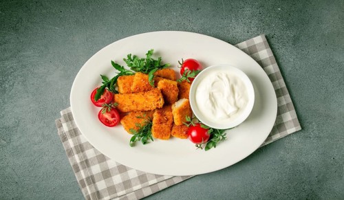 Fried fish nuggets, with white sauce, arugula and cherry, no people
