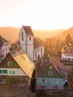 A village with a church and half-timbered houses in the soft sunset light creates an idyllic scene,