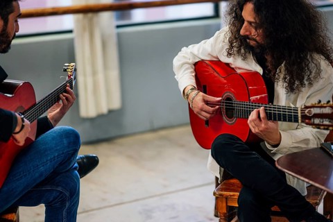 From above male friends playing guitars at table in music studio