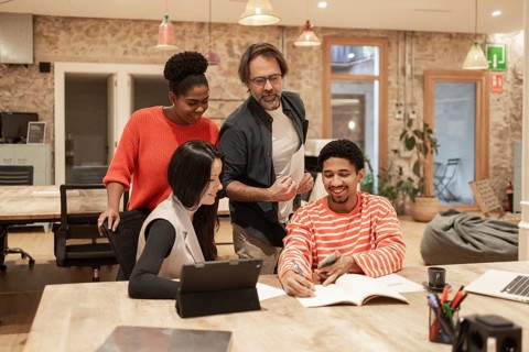 A diverse team collaborates energetically in a modern coworking space The warm ambiance and