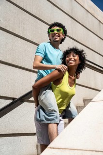 A lively multiethnic LGBTQ+ couple shares a joyous moment outdoors, showcasing happiness and