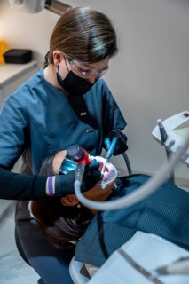Dentist using specialized equipment for teeth whitening procedure on patient, demonstrating