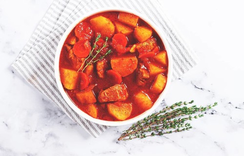 Meat goulash with potatoes and carrots, sweet peppers, in a saucepan, top view, traditional