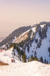 A group of hikers climb a snow-covered mountain trail that stretches to a majestic peak, Hochgrat