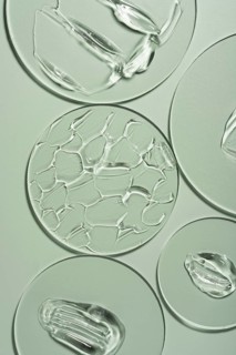 Top view of transparent gel smears on laboratory glass arranged over a soft green background,