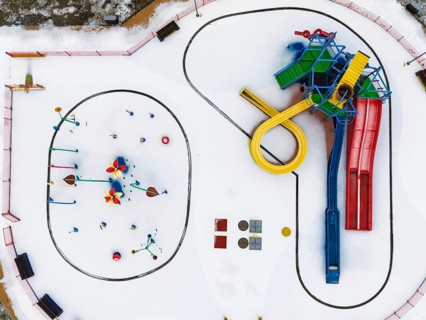 Minimalist top-down drone shot of colorful pool slides and equipment standing out against a clean,