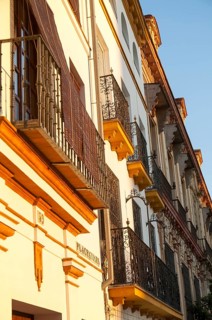 Late afternoon golden sunlight falling of historic houses in Placentines street, central Seville,