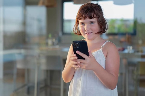 Young girl enjoying a sunny day outdoors while engaging with her smartphone. She is relaxed,