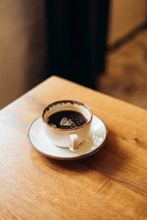 A ceramic coffee cup filled with rich black coffee, topped with delicate latte art foam, rests on a