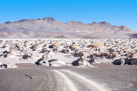 A captivating view of a curvy highway through La Puna's vast desert in Argentina, surrounded by