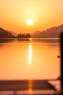 Calm lake with sunset, reflecting water surface, surrounded by mountains, Großer Alpsee, Immenstadt