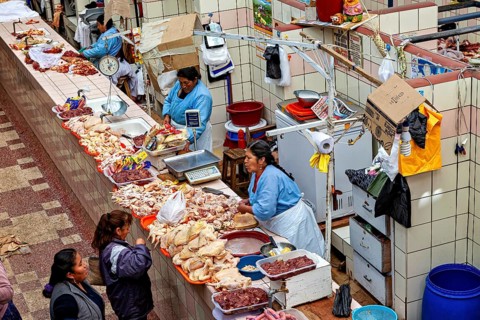 Women sell meat products in a covered, colorful market stall, The stalls in the market halls of